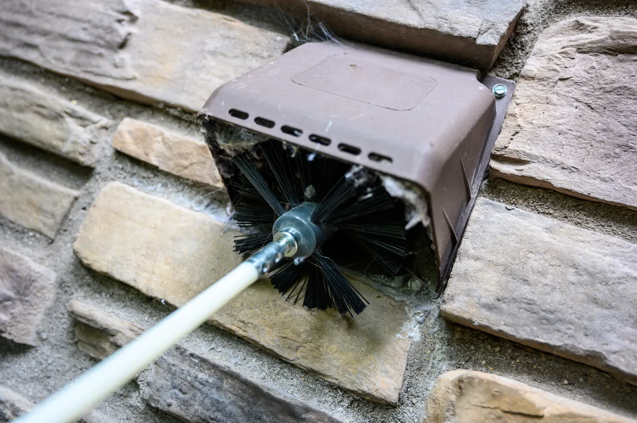 Professional dryer vent cleaning brush removing lint from an exterior vent in Omaha, Nebraska